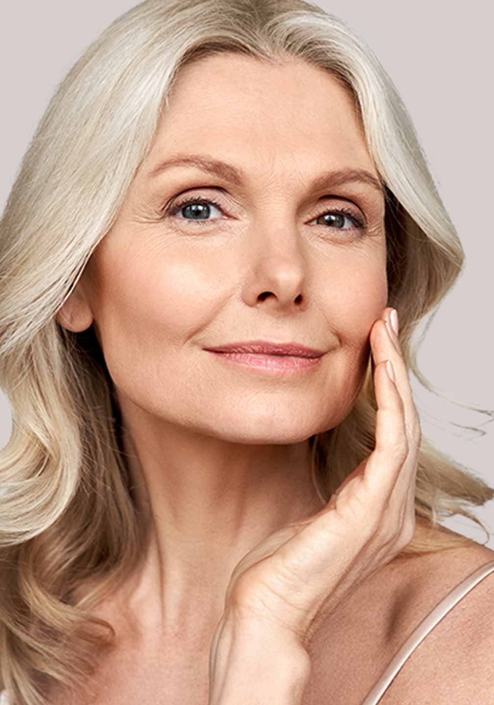 Reife Frau mit silbernem Haar präsentiert ihre Schönheit und wirbt für die Vorteile der Bakuchiol-Gelmaske „Firm it!“ von RAU Cosmetics.